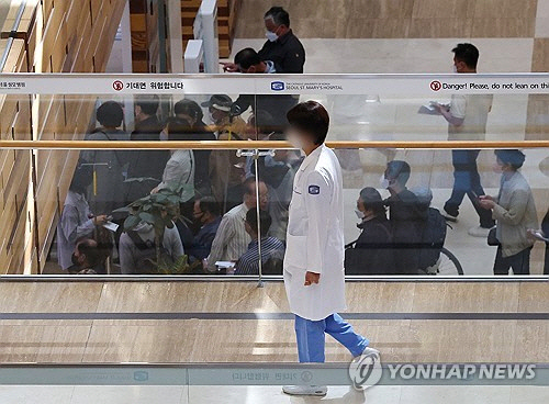 보건의료정책심의위원회 회의록 등 의대 증원의 근거자료를 두고 정부와 의료계가 연일 공방을 이어가는 가운데 13일 서울 시내 한 대형병원 로비에서 한 의료관계자가 이동하고 있다. [연합뉴스]